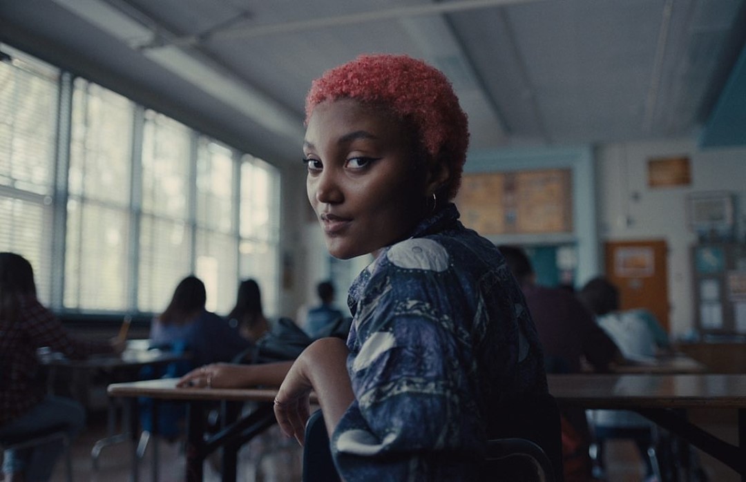 a woman with pink hair sitting in a classroom
