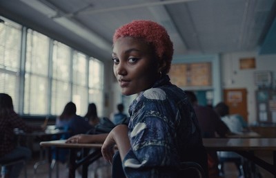 a woman with pink hair sitting in a classroom