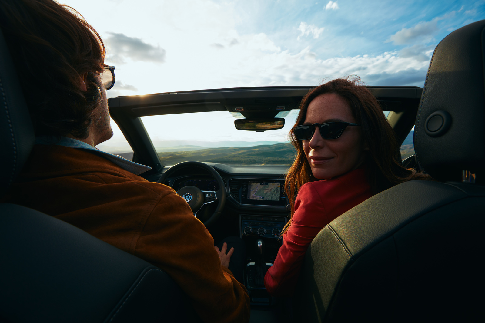 a man and a woman sitting in a car looking at each other