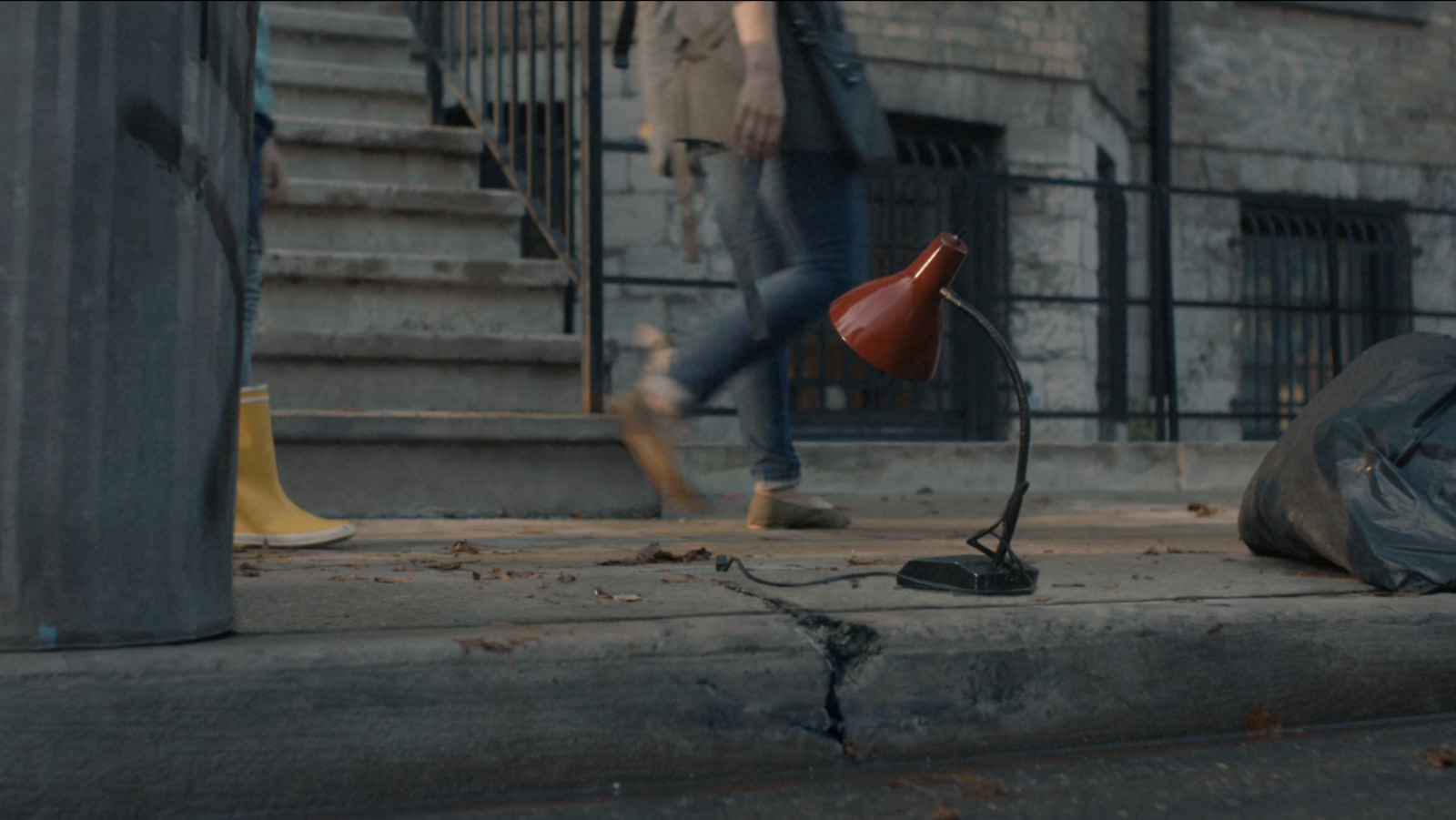 a person walking down a street next to a red lamp