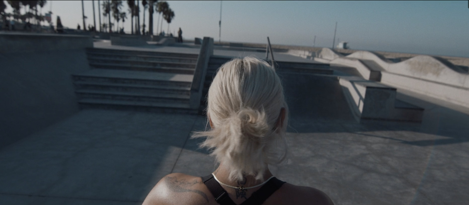 a woman with white hair standing in front of a skate park