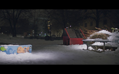 a park bench covered in snow next to a pile of snow