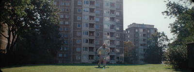 a man standing in the grass in front of a tall building