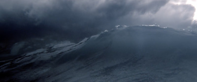 a large wave in the ocean under a cloudy sky