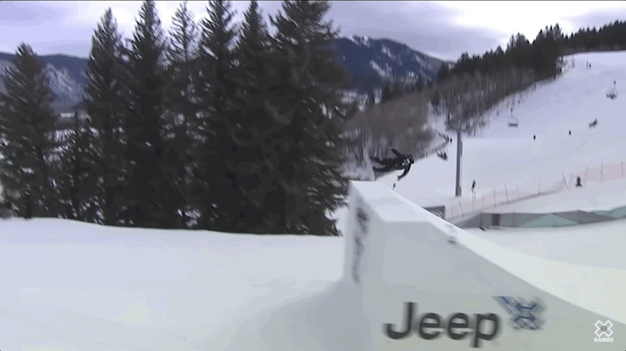 a man riding a snowboard down the side of a snow covered slope