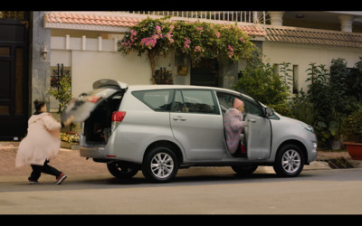 a woman walking past a silver car with its door open