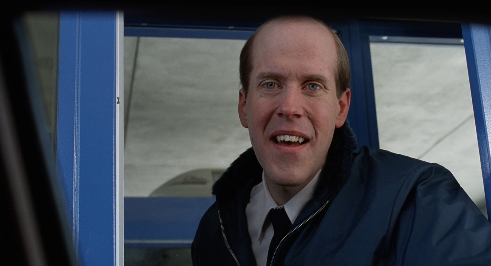 a man in a jacket and tie looking out of a window