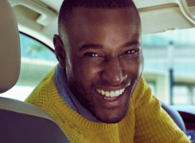 a smiling man in a yellow sweater in a car