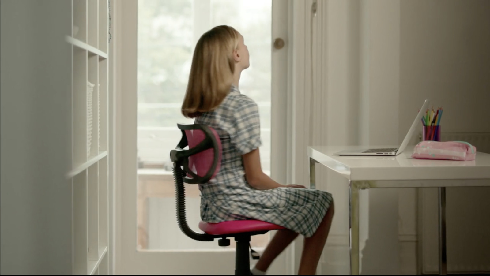 a little girl sitting at a desk with a laptop