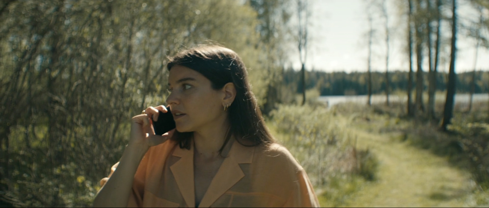 a woman talking on a cell phone in a wooded area