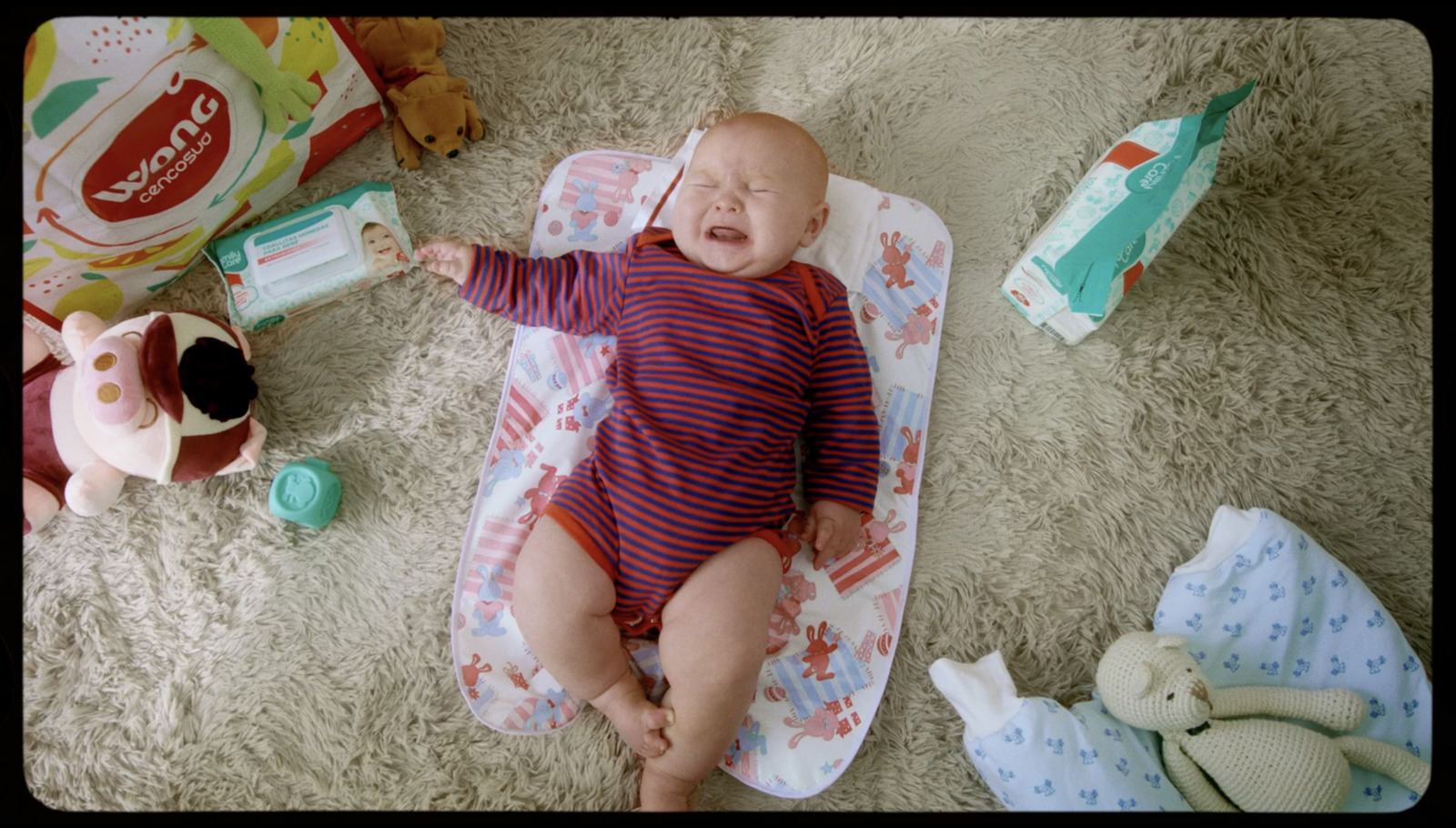 a baby laying on top of a blanket next to stuffed animals