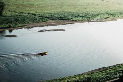 a boat traveling down a river next to a lush green field