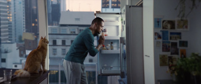 a man standing in front of a refrigerator next to a cat