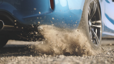 a blue car driving down a street next to a pile of dirt