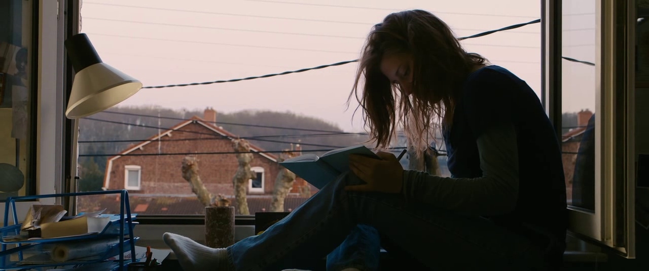 a woman sitting on a window sill reading a book