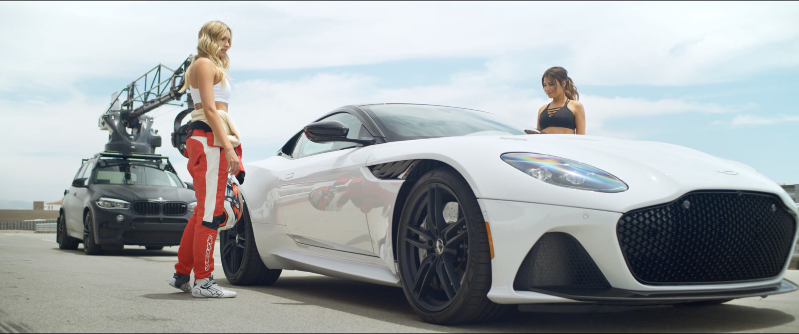 two women standing next to a white sports car