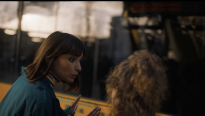 a woman standing next to another woman in front of a bus