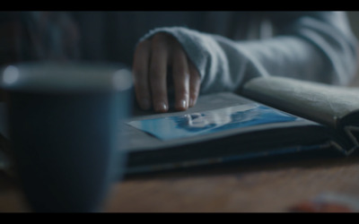 a person sitting at a table with a book and a cup of coffee