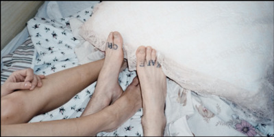 two people laying in bed with their feet on a pillow