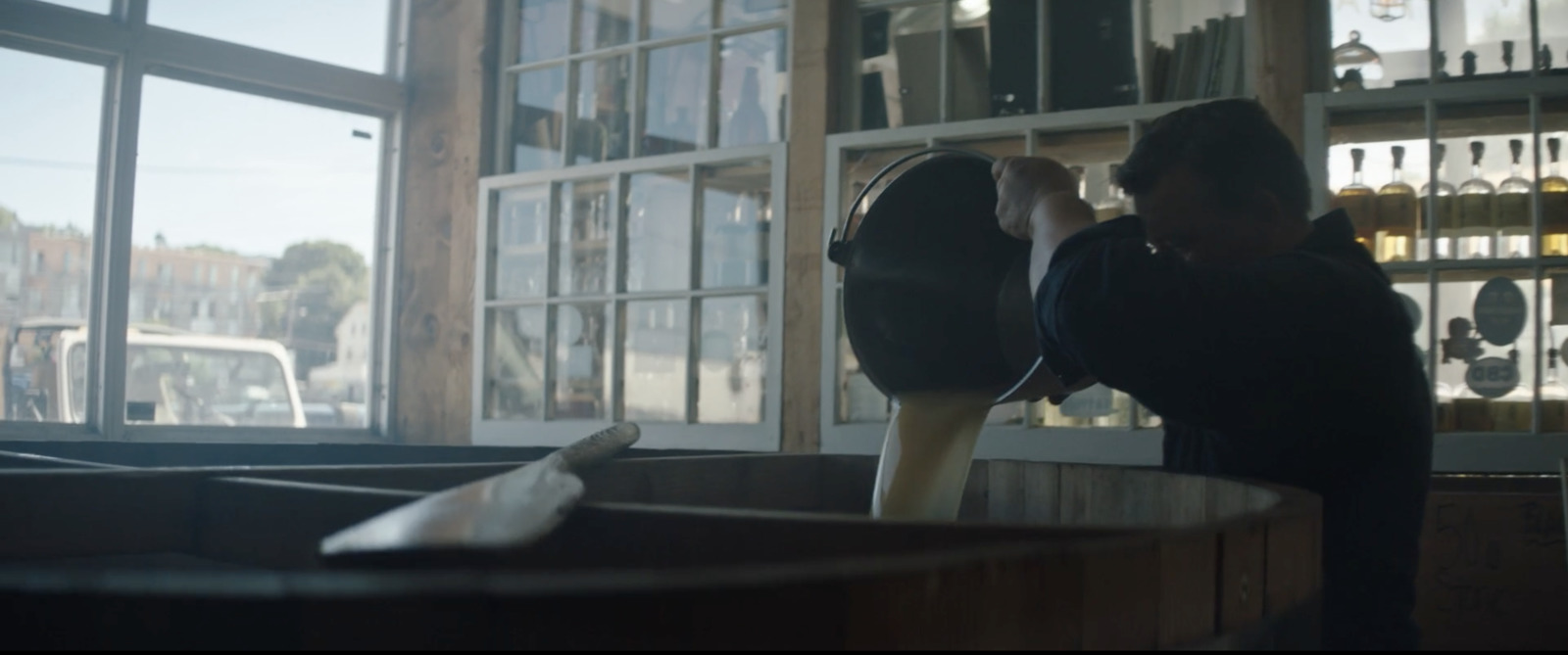 a woman standing in front of a window next to a wooden barrel