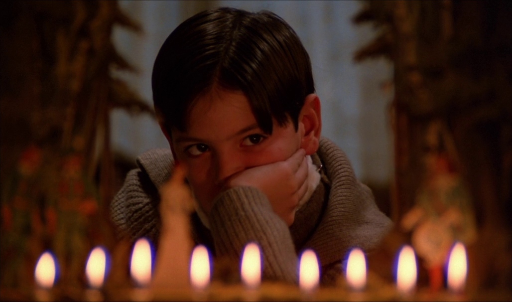 a young boy sitting in front of a bunch of lit candles