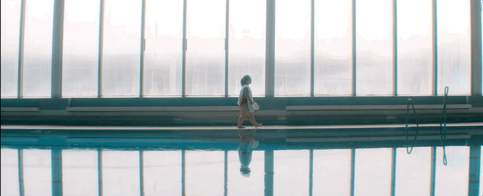 a woman walking by a swimming pool in a building