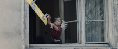 a woman holding a skateboard up to a window