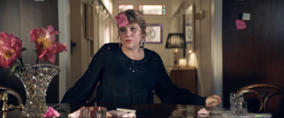 a woman sitting at a table with a pink flower in her hair