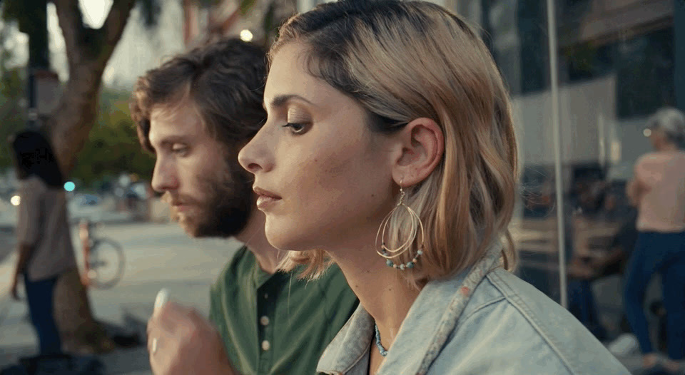 a man and a woman are looking at their cell phones