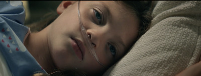 a young girl laying on top of a bed next to a stuffed animal