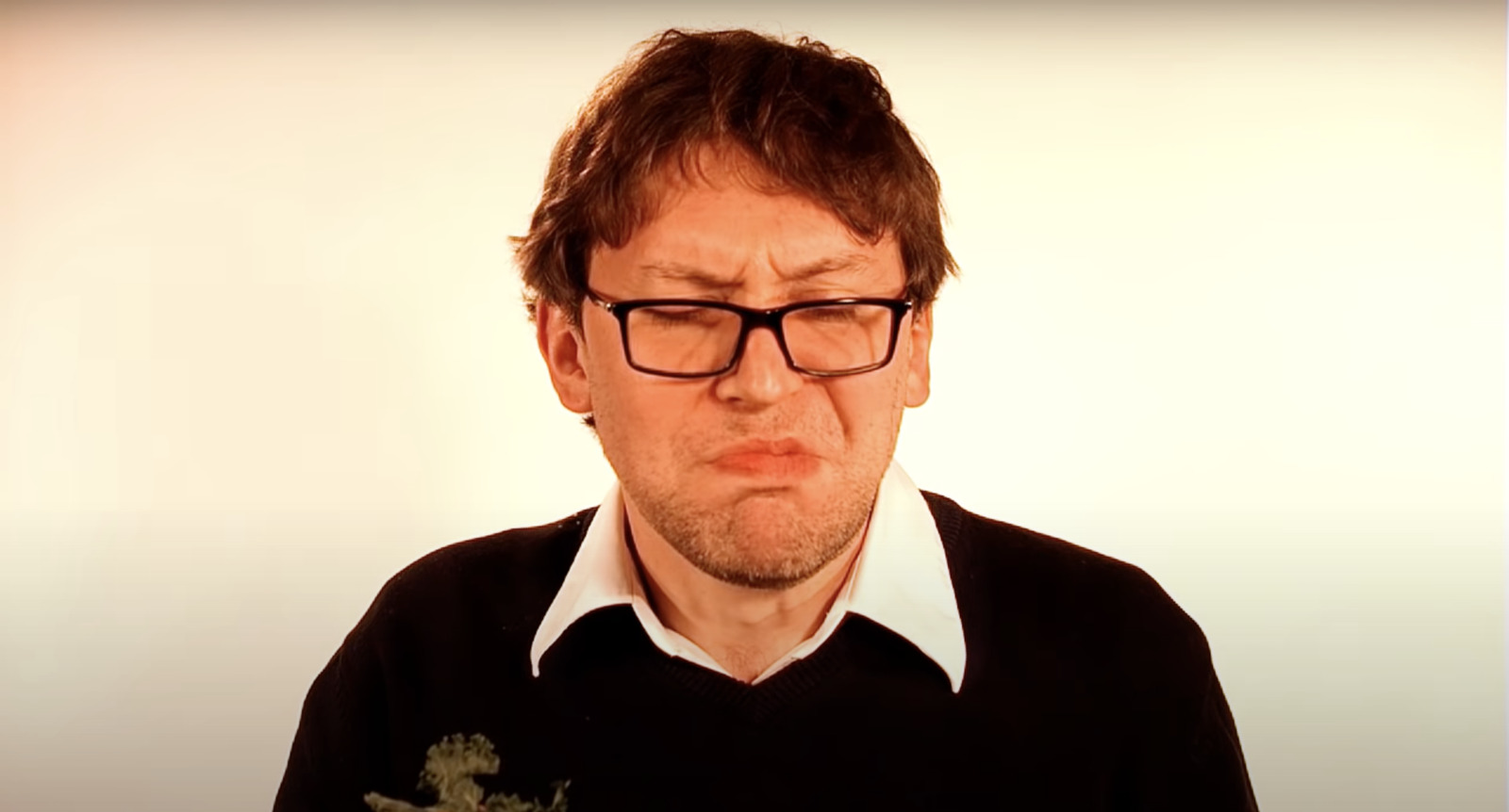 a man with glasses holding a flower in front of his face