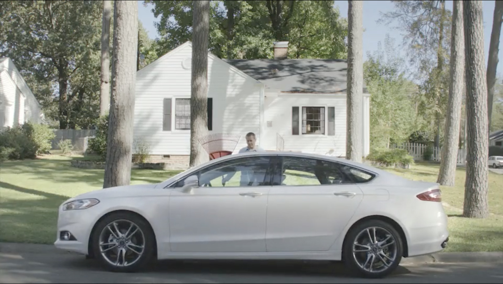 a white car parked in front of a white house