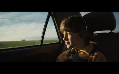 a boy wearing headphones sitting in a car