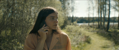 a woman standing in the woods talking on a cell phone