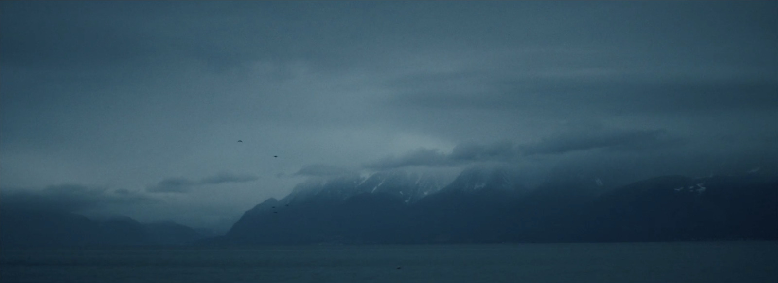 a large body of water with mountains in the background