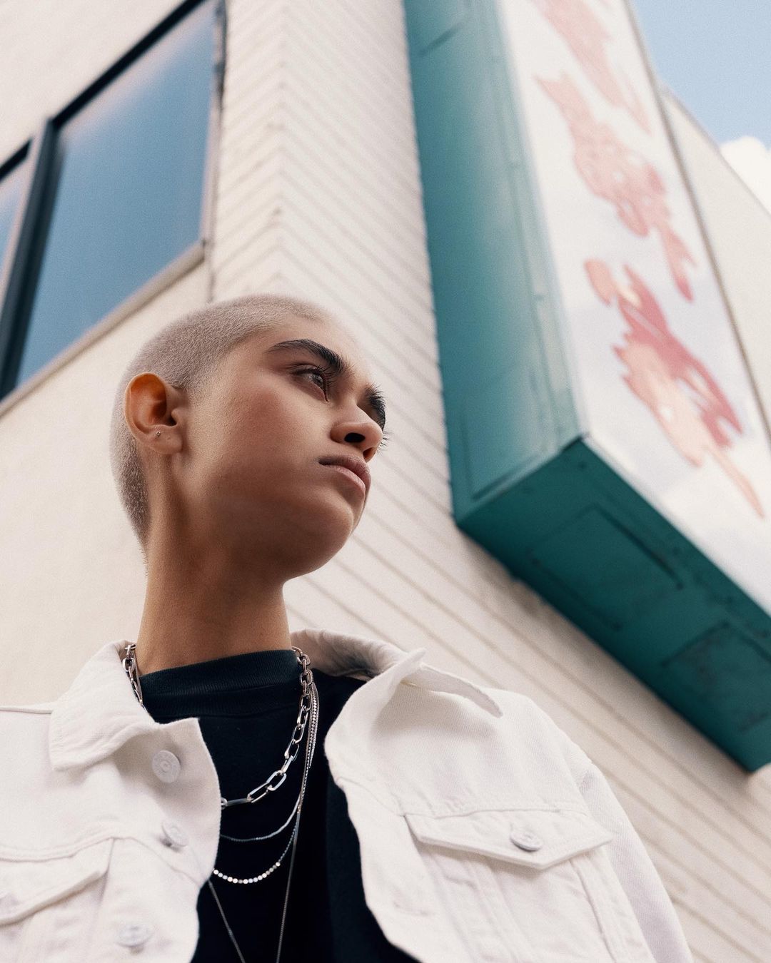 a man with a shaved head standing in front of a building