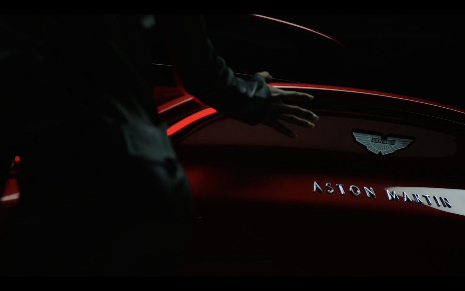 a man standing next to a red car in the dark