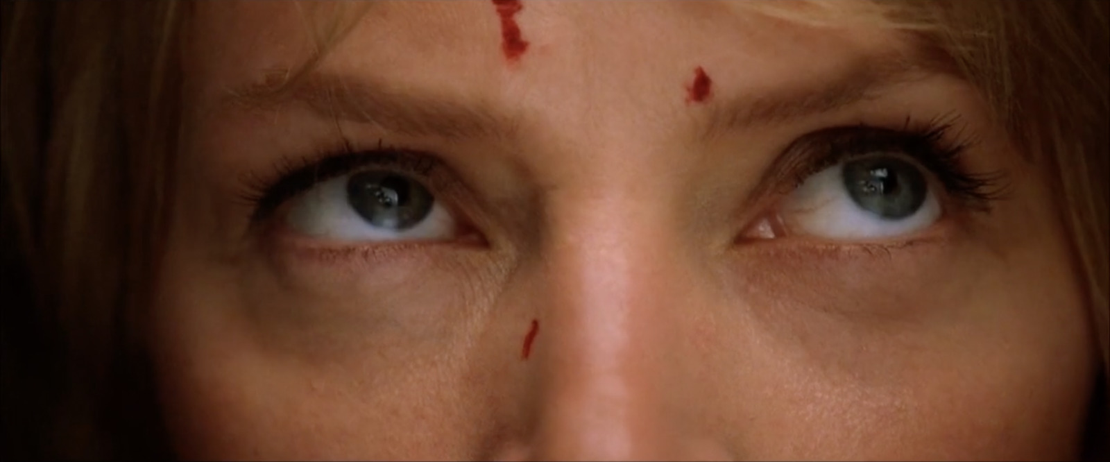 a close up of a woman's face with blood on her forehead