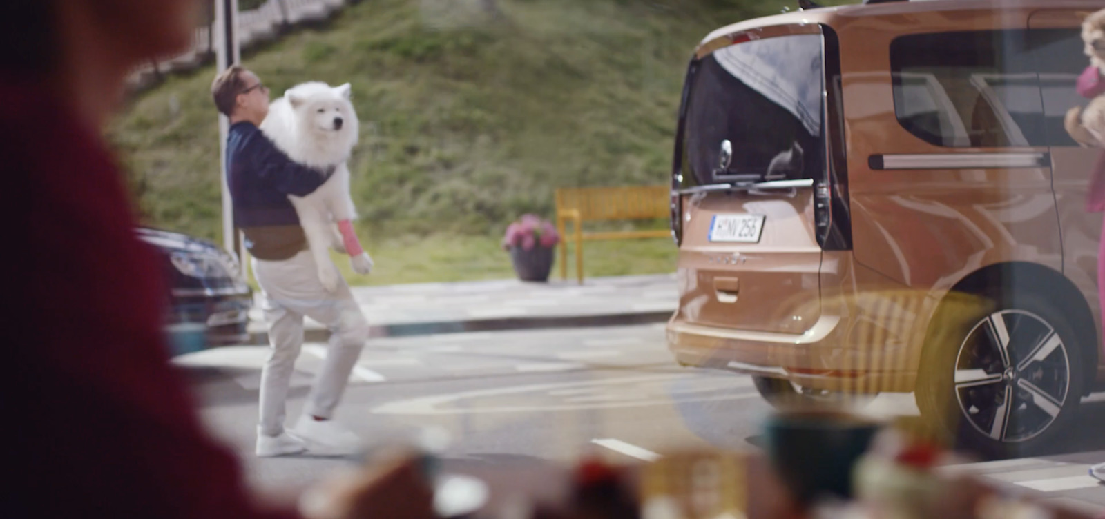 a man walking a dog in front of a van