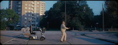 a man walking across a street next to a scooter