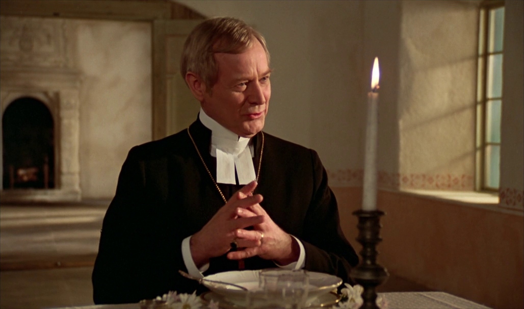 a priest sitting at a table in a church