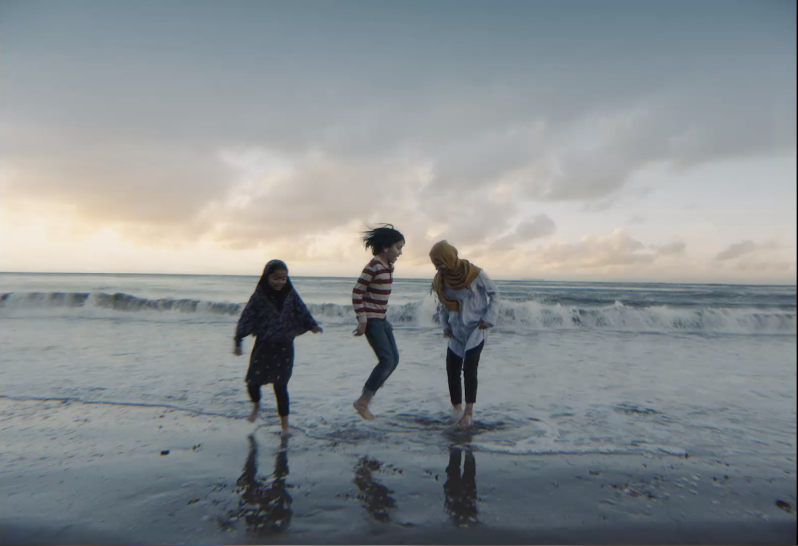 a group of three girls walking along a beach