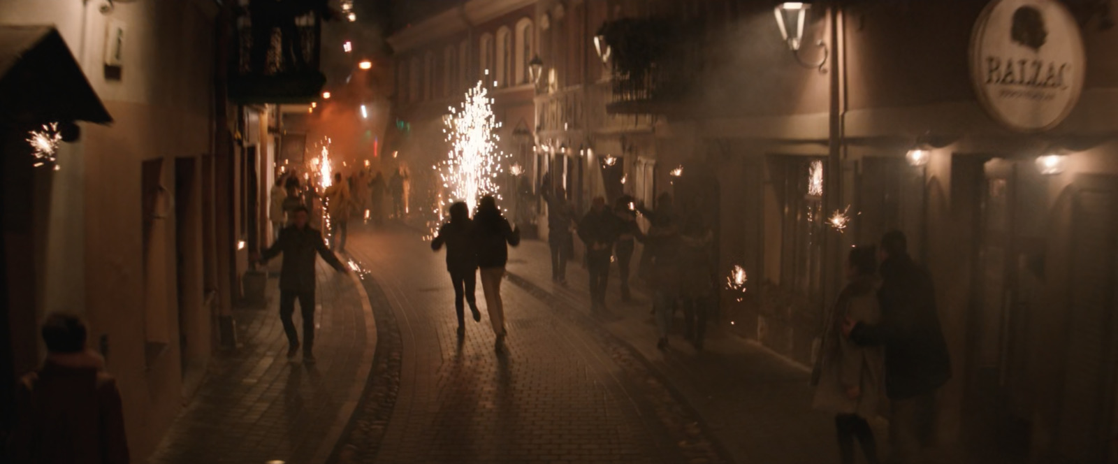 a group of people walking down a street at night