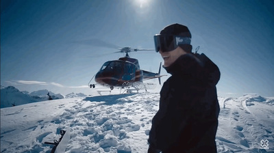 a man standing on top of a snow covered slope next to a helicopter