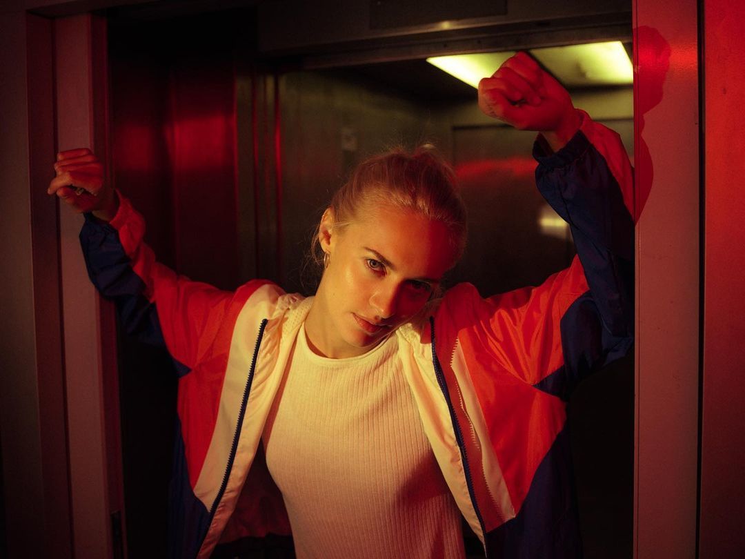 a woman in a red and blue jacket standing in a doorway