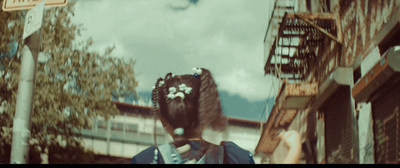 a woman with a flower in her hair standing in front of a building