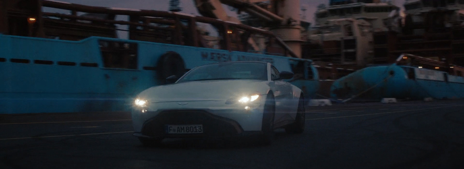 a white car driving down a street next to a boat