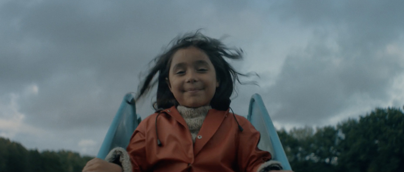 a little girl sitting in a chair with her hair blowing in the wind