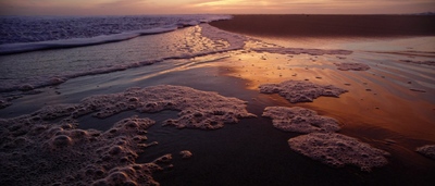 the sun is setting over the water at the beach