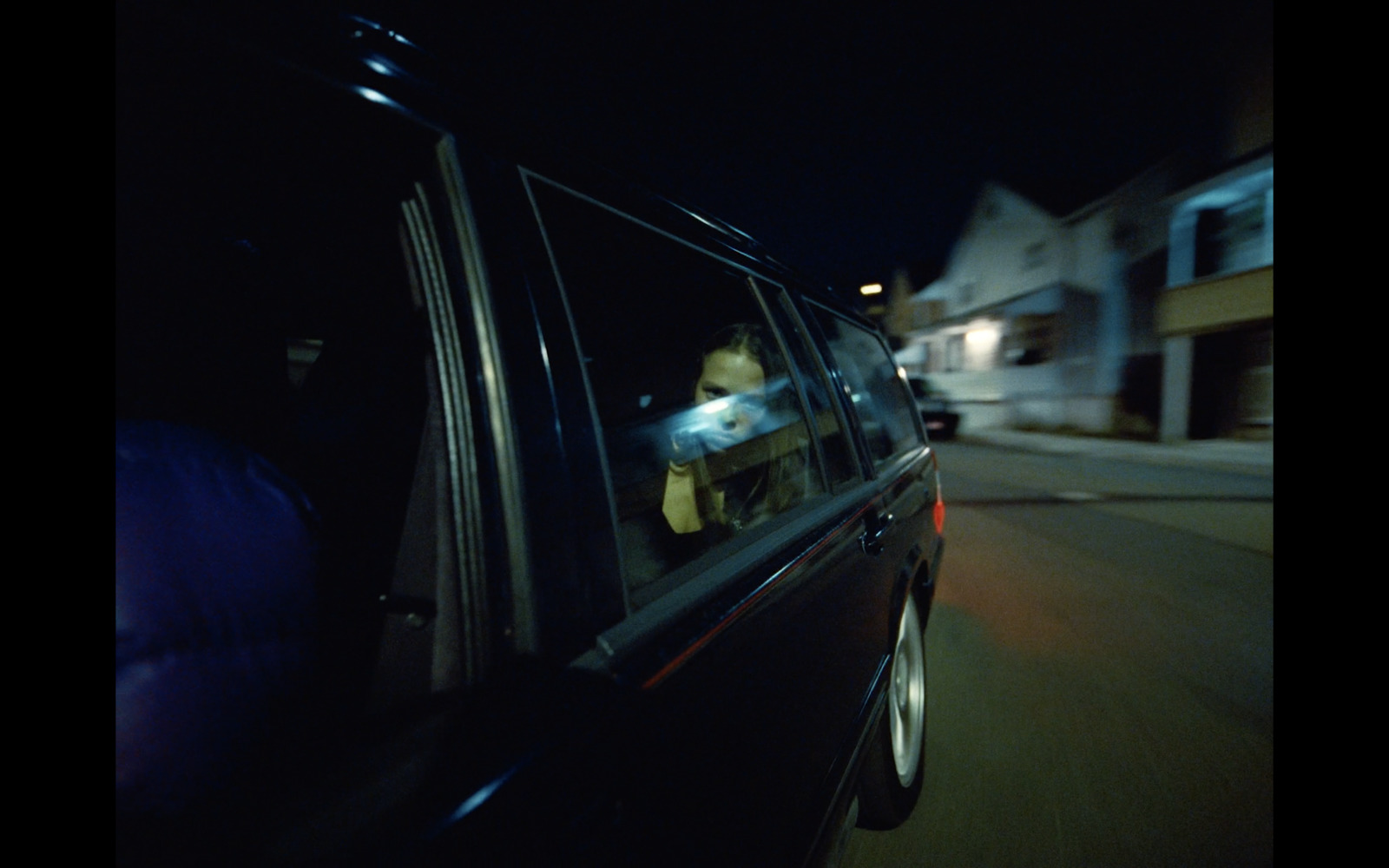 a man in a car driving down a street at night